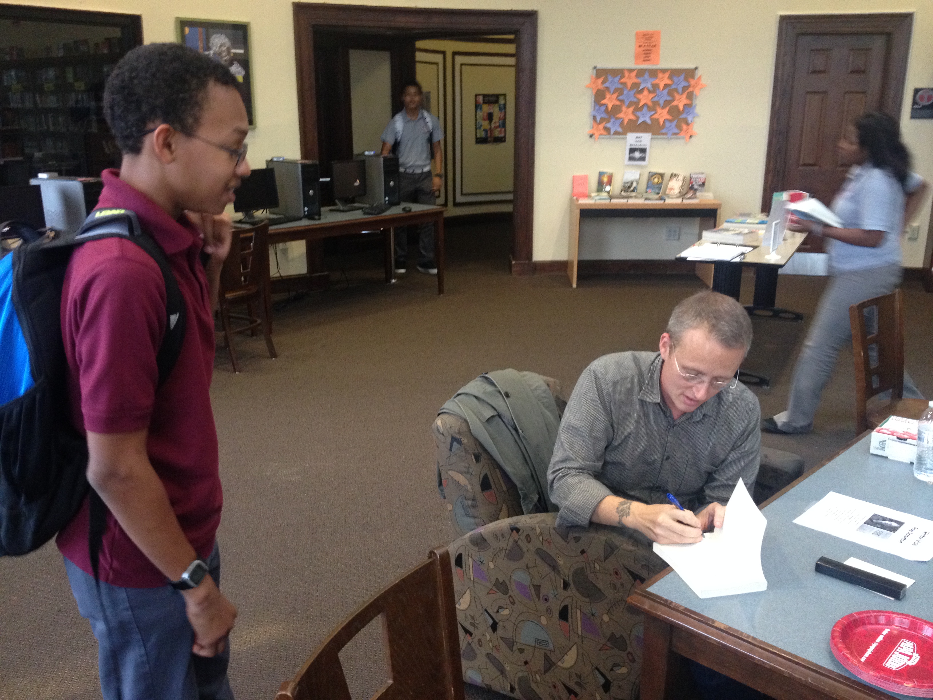 Roy Scranton signs a copy of the anthology he edited for a student following his Writers in Schools Visit https://www.penfaulkner.org/wp-content/uploads/2013/10/Roy-Scranton-signs.jpg