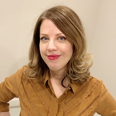 Headshot of Amber Sparks, a White woman wearing red lipstick and a yellow top