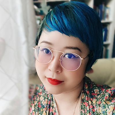 Headshot of author Esmé Weijun Wang, an Asian woman with blue hair, glasses, red lipstick and wearing a floral patterned top