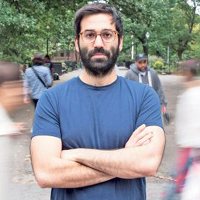 Headshot of author Zack McDermott, a White man wearing glasses and a blue t-shirt