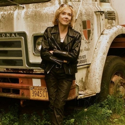 Headshot of Elizabeth Hand, a White woman wearing a black leather jacket leaning against a truck