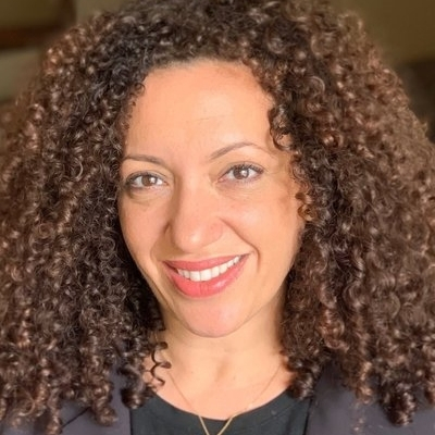 Headshot of Hannah Allam, a smiling Arab woman wearing a black jacket