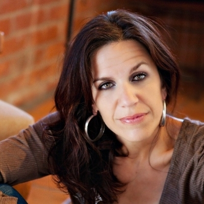 Headshot of author Laila Halaby, a Middle Eastern woman wearing hoop earrings and a gray top