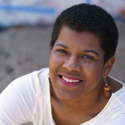 Headshot of author Tananarive Due, a smiling Black woman with short hair wearing a white top