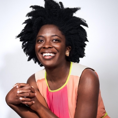 Headshot of author Yaa Gyasi, a smiling Black woman wearing a colorful sleeveless top