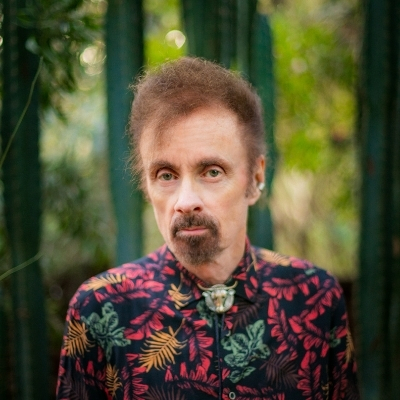 Headshot of author T.C. Boyle, a White man wearing a colorful printed shirt