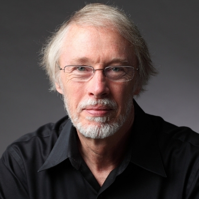 Headshot of writer Charles Baxter, a White man wearing glasses and a black shirt