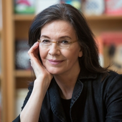 Headshot of author Louise Erdrich, a person wearing glasses with shoulder-length brown hair wearing a black collared top