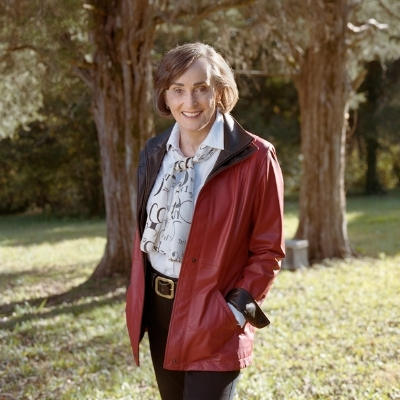 Headshot of Margaret Verble, a person with a short bob wearing a printed scarf and red jacket