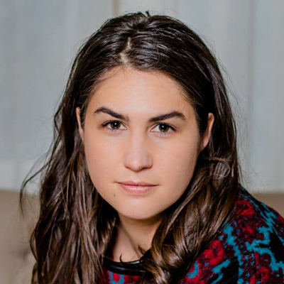 Headshot of author Azareen Van der Vliet Oloomi, an Iranian-American woman with long dark hair wearing a colorful top