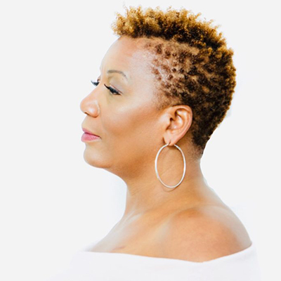 Headshot of Bernice L. McFadden, a Black woman wearing hoop earrings and a white top