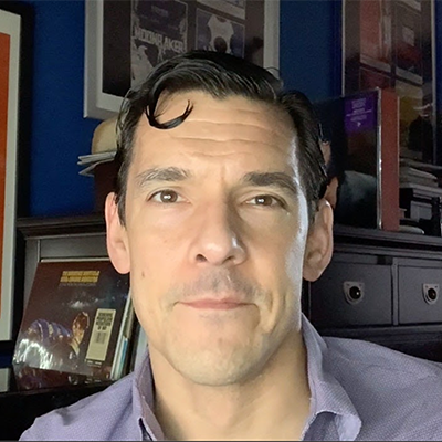 Headshot of Chris Klimek, a White man wearing a purple gray collared shirt