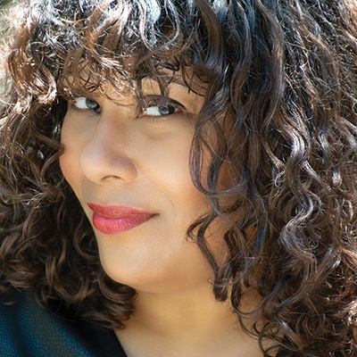 Headshot of author Ivelisse Rodriguez, a Latin woman with long curly hair wearing red lipstick
