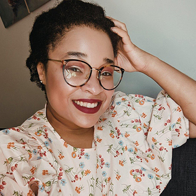 Headshot of Morgan Jerkins, a Black woman with glasses, wearing red lipstick and a floral top