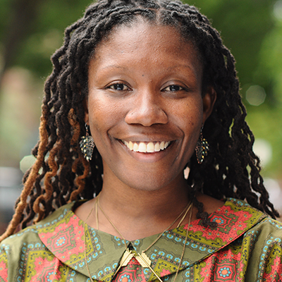 Headshot of author Nicole Dennis-Benn, a smiling Black woman wearing a colorful patterned top