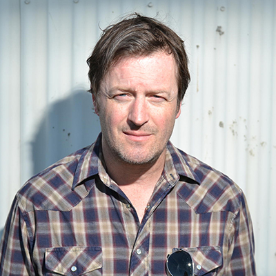 Headshot of author Willy Vlautin, a White man wearing a plaid collared shirt